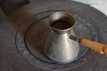 Hot coffee prepared in a Turk. Top view on a beautiful curled foam. Authentic process of preparation of coffee. Coffee brewer. Selective focus