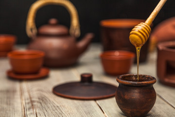 Obraz na płótnie Canvas Tea ceremony, tea party. Clay dishes. Honey flows from a wooden spoon into a pot