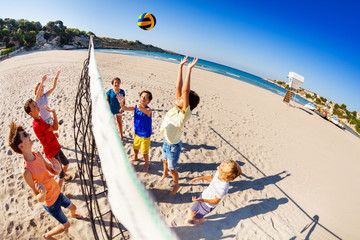 Happy children playing volleyball on the beach