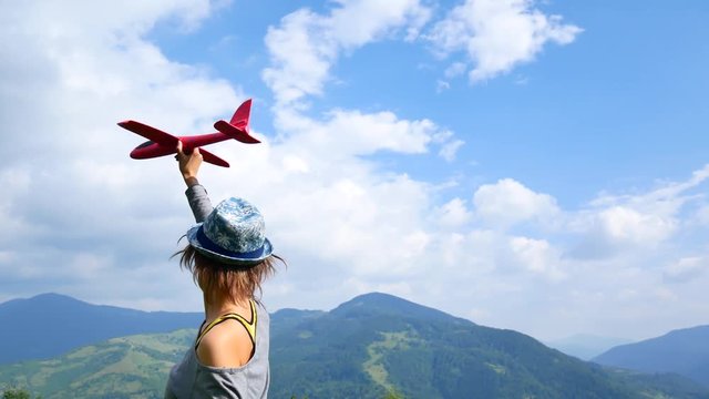Young pretty woman back to the camera and keeps the red model of the plane in ruach. concept of travel and freedom.
