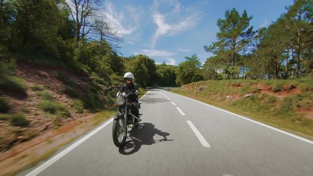 Beautiful epic shot of young determined and empowered woman driving black vintage motorcycle down empty mountain road in search of adventures and freedom, on road lifestyle and travel