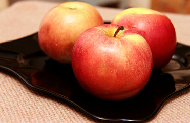 Red apples on the black plate on the table