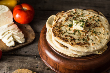 Pita bread on wooden board with feta cheese and tomatoes and pepper. Still life of food. Georgian cuisine. Spanish food. National cuisine. Traditional dish on wooden table. Mediterranean cuisine.