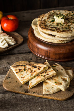 Pita bread on wooden board with feta cheese and tomatoes and pepper. Still life of food. Georgian cuisine. Spanish food. National cuisine. Traditional dish on wooden table. Mediterranean cuisine.
