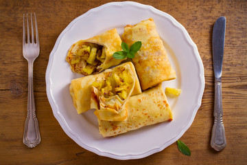 Delicious homemade crepes filled with apples and cinnamon. overhead, horizontal