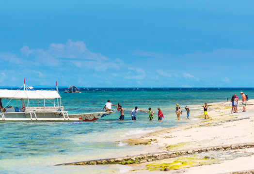 MOALBOAL, PHILIPPINES - FEBRUARY 20, 2018: Boat and a group of tourists near the shore. Copy space for text.