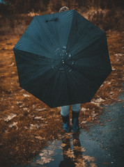 Woman hidden behind the umbrella in forest in autumn