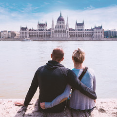 A couple in love sits on the embankment and enjoys the view of Parliament in Budapest, Hungary