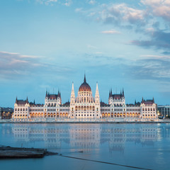 Obraz premium Parliament building in Budapest, Hungary. Building facade with reflection in water. Beautiful picture at sunset