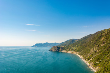 Fototapeta na wymiar Ocean view with sun illuminating curvy coastline with hills. Cinque terre, Italy.