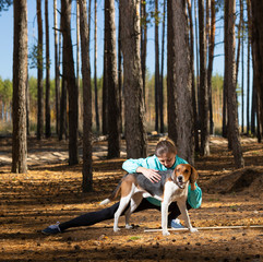 A young girl doing exercises in nature with dog.