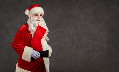 Happy funny Santa Claus with red sock on gray background.