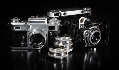 two vintage cameras and lens on a black background