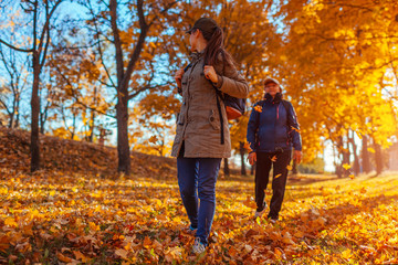 Tourists with backpacks walking in autumn forest. Mother and her adult daughter travelling together