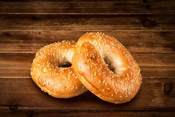 Fresh sesame seed bagel bread, isolated on a vintage wooden table in background.