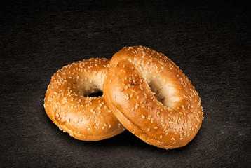 Fresh sesame seed bagel bread, isolated on a natural slate stone in background.