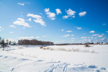 Winter landscape. Countryside. Frozen river. Sunny day. Blue sky. White clouds.