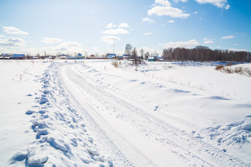 Winter landscape. Countryside. Snowy road. Sunny day. Blue sky. White clouds.