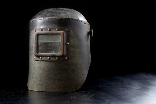 An Old Mask A Protective Suit For A Welder. Occupational Health And Safety Clothing For Production Workers On A Workshop Table.