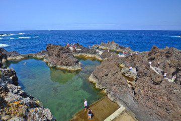Fototapeta na wymiar Coastline with volcanic rocks and natural lava rock pools in Porto Moniz, Madeira, Portugal