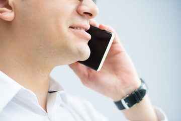 Close-up of confident businessman talking on mobile phone. Smiling optimistic male manager calling business partner. Entrepreneur concept
