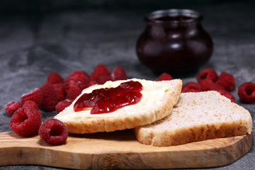 Toast bread with homemade raspberry jam or marmalade on rustic table served with butter for breakfast or brunch