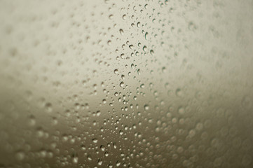 raindrops on window glass on background of cloudy sky