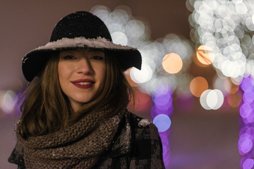 Young girl walking in front of trees decorated with colorful lights for christmas night, blurred in the background