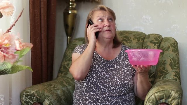 Shocked Woman Calling Plumber While Collecting Water Leaking From Ceiling Using Utensil