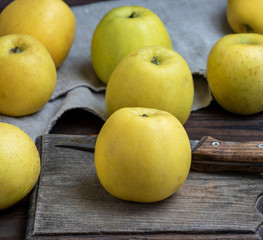 ripe whole yellow apples on a brown wooden board