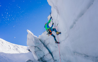 Epic shot of an ice climber climbing on a wall of ice. Mountaineer and climber on an adventure...