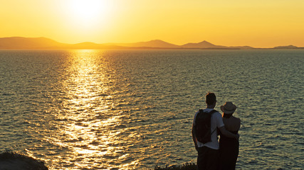 A young couple admiring the sunset on the beach