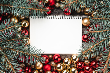 Christmas card. Fir branches. Red and gold baubles. Message book. Top view.