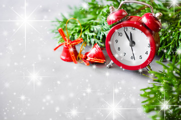 Christmas composition: xmas fir branches, alarm clock and red bells.