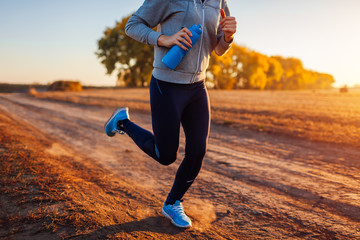 Woman running in autumn field at sunset. Healthy lifestyle concept. Active sportive people
