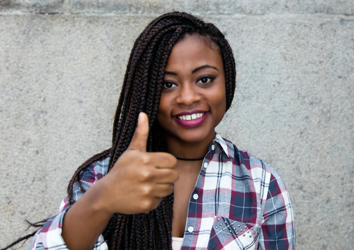Laughing african american woman with dreadlocks showing thumb up