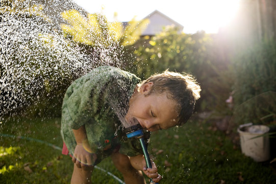 Portrait of a small boy playing with a sprinkler.