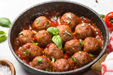 Meatballs in tomato sauce on white table.