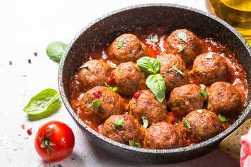 Meatballs in tomato sauce on white table.