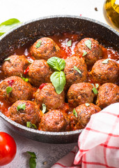 Meatballs in tomato sauce on white table.