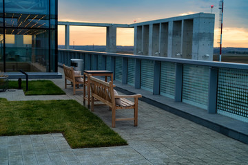 Modern rooftop patio with wooden benches in evening