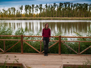 A teenage girl in a viewpoint with a wooden railing contemplating a river in autumn