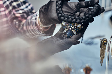 Close-up photo of a jewelry worker presenting a costly necklace with gemstones in a jewelry store.
