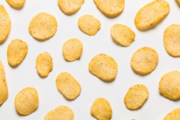 Crispy potatoes chips isolated on white background. Food background. Potato chips lying at a distance from each other on a white table.