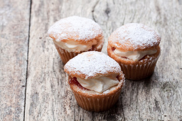 Cupcakes stuffed with white cream on wooden table