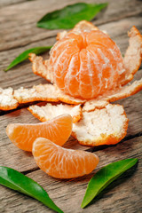 ripe and juicy mandarines (tangerine) and green leaves on wooden background.