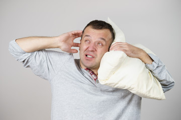 Sleepy man with pillow closing his ear