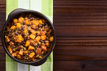 Homemade chili con carne with mincemeat, red and black beans, tomato sauce and pumpkin in rustic bowl, photographed overhead with copy space on the side (Selective Focus, Focus on the chili)