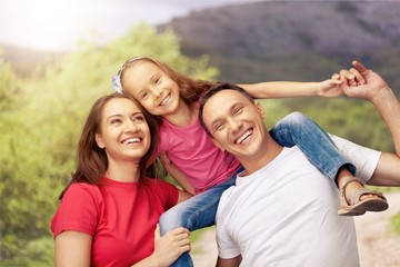 Fototapeta premium Happy smiling family with daughter over green trees background