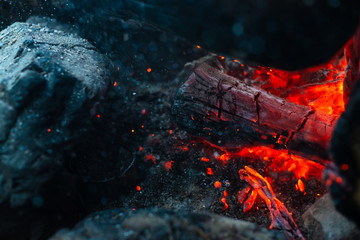 Smoldered logs burned in vivid fire close up. Atmospheric background with orange flame of campfire....